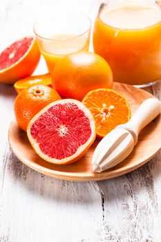 The preparation for citrus juice for breakfast. Wooden  citrus reamer with fruits.