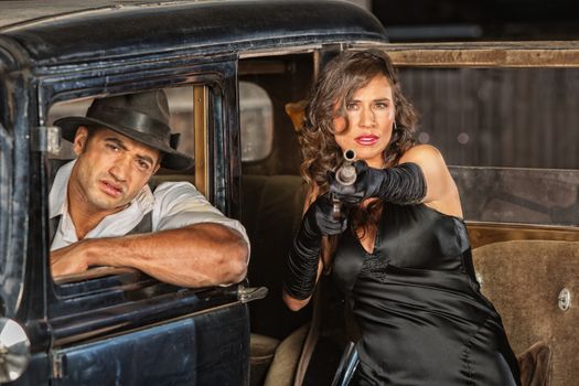 Dangerous 1920s vintage gangsters at car with shotgun
