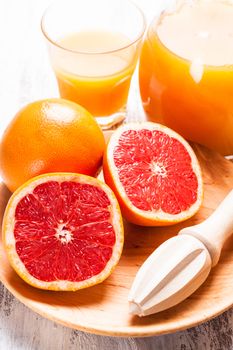 The preparation for grapefruit juice for breakfast. Wooden  citrus reamer with fruits.