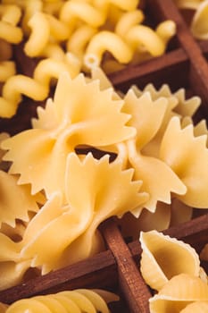 Various pasta  types in the wooden box on the table. Close up farfalle