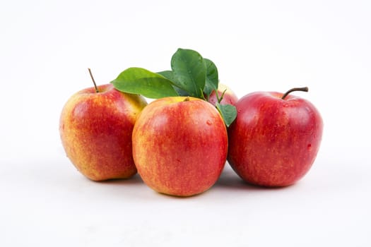 Fresh apples with leaves on a white background.