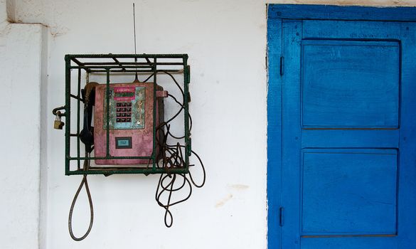 Street phone behind a lattice under the lock. Congo. Africa