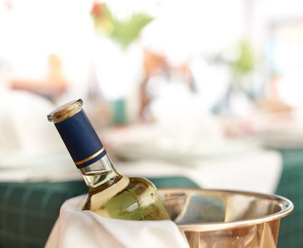 Bottle of cold white wine in ice on restaurant table