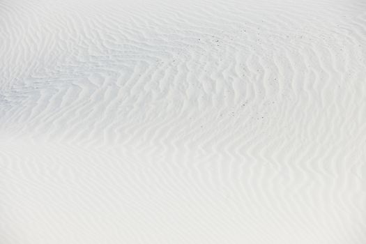 White quartz sand with wind waves on its surface