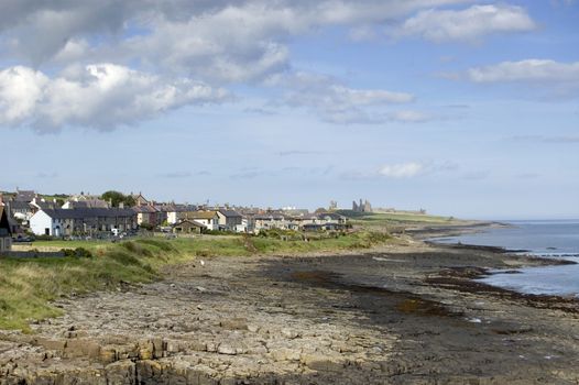 The Northumbrian village of Craster with the ruins of Dunstanburgh Castle in the distance