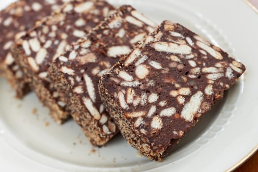 Slices of sweet cake with bisquits and cacao in a porcelain white dish