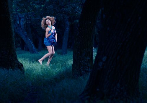 Young girl dancing in dark woods, forest fairy at midnight
