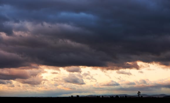 Sunset landscape with dark storm clouds after autumn rain