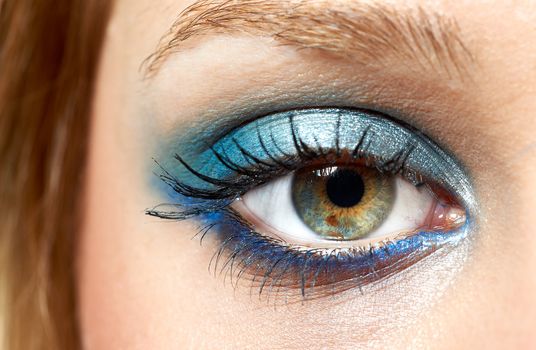 Beautiful eye with blue makeup; young girl eyeball macro and beautiful skin color