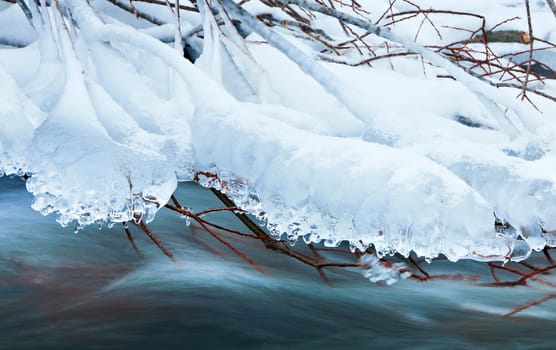 Ice over blue water of mountain stream in winter season