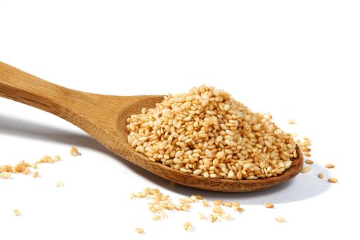 Sesame grains in large wooden spoon on white background