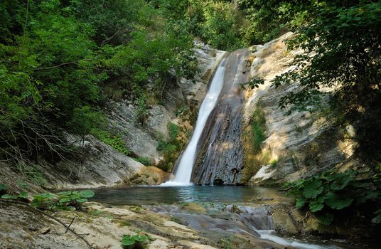 Waterfall on small stream in green summer forest