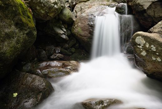 Waterfall on mountain stream, running between stones