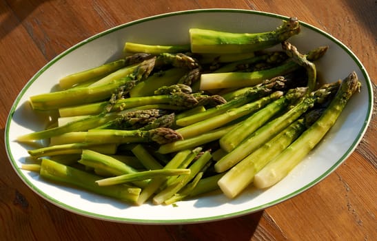 Boiled green asparagus sprouts in white dish ready to be served salted