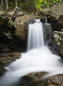 Little waterfall on a spring mountain stream, smooth water