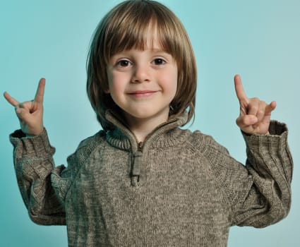 Little happy boy makink rock sign with hands