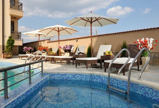 Swimming pool, lounges and umbrellas in hotel yard