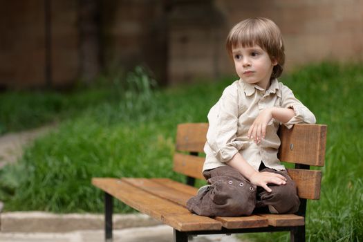 Little cute boy on a bench, looking aside