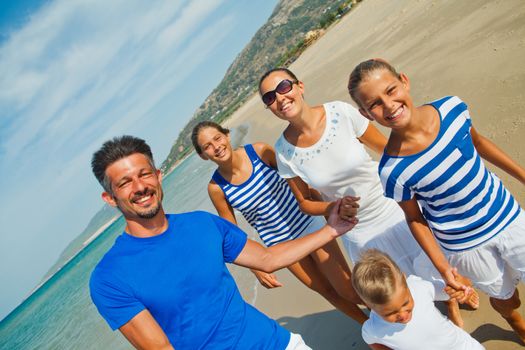 Photo of happy family with three kids running down the beach