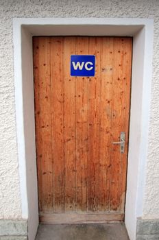 Close up on closed wooden door with WC sign