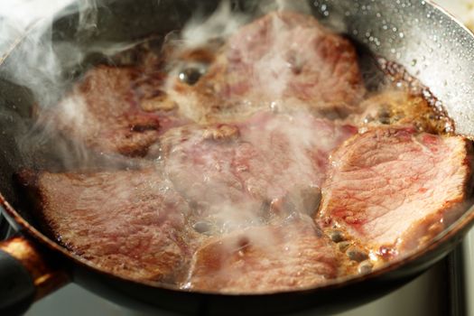 Frying fresh veal fillet in a frying pan and some vapour