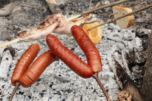 Roasting sausage on open charcoals of open fire