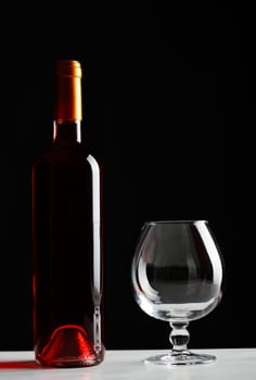 Bottle of red wine and an empty glass on table