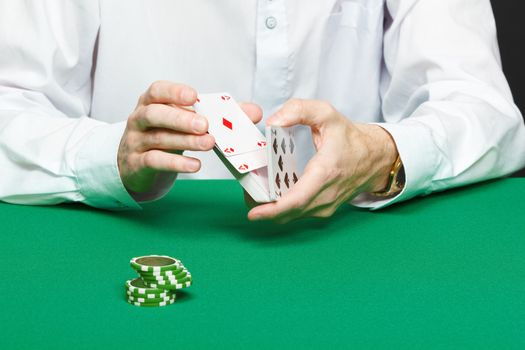 gambler. Male hand with cards and chips on green table