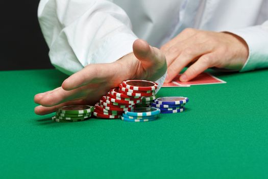 gambler. Male hand with cards and chips on green table