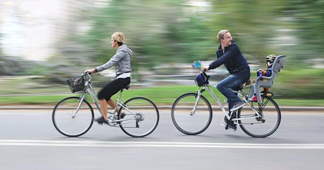 New York, USA - OCT 16, 2013: Young family with baby moving along the streets in New York by bicycles. Image in motion blur style.