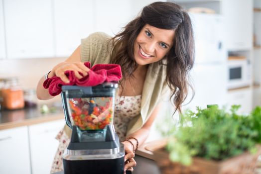 Attractive woman preparing vegetables in the blender