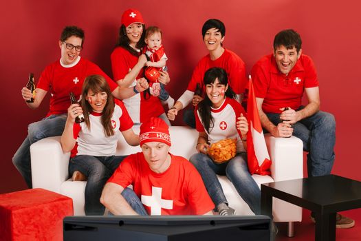 Photo of Swiss sports fans watching television and cheering for their team.