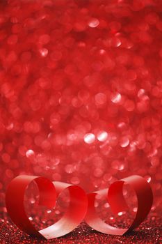 Red ribbon hearts on shiny glitter background