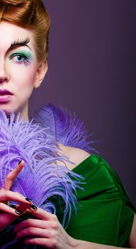 Attractive young girl with a fabulous makeup and feathers close-up portrait