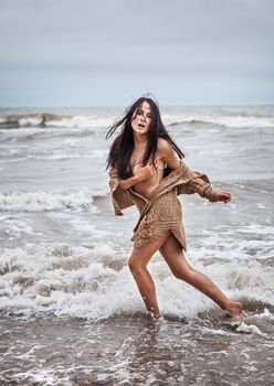 Beautiful young seminude woman in the cold sea waves