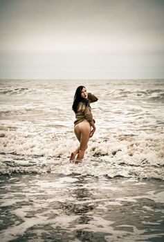 Beautiful young seminude woman in the cold sea waves.  Intentional color shift and small film grain