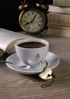 Heart shaped lock and key hanging on the handle of a cup of coffee