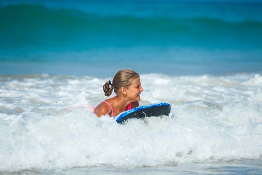 Summer vacation - Happy cute girl having fun with surfboard in the ocean