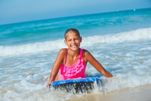 Summer vacation - Happy cute girl having fun with surfboard in the ocean