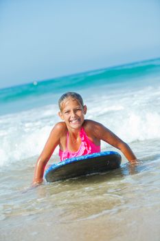 Summer vacation - Happy cute girl having fun with surfboard in the ocean