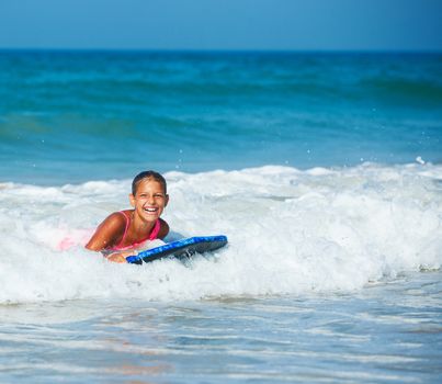 Summer vacation - Happy cute girl having fun with surfboard in the ocean