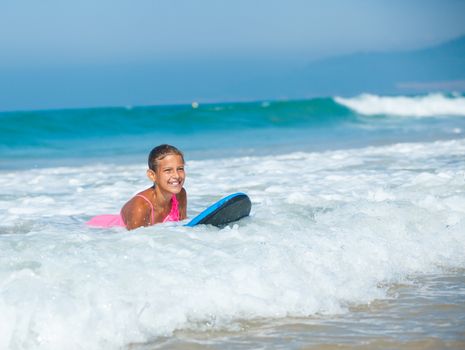 Summer vacation - Happy cute girl having fun with surfboard in the ocean