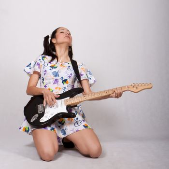 Woman in colorful retro dress, passionately plays the electric guitar