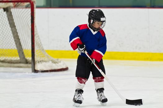 Child skating with a puck at ice hockey practice