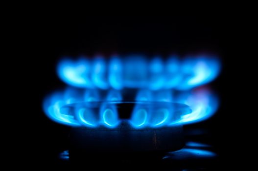 Blue gas flames from two stove burners in the dark