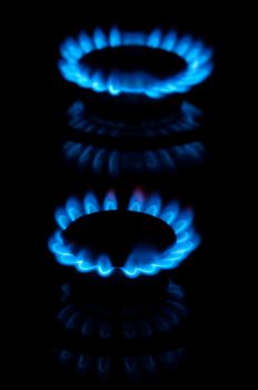 Blue gas flames from two stove burners in the dark