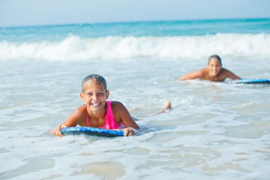 Summer vacation - Happy cute girl having fun with surfboard in the ocean