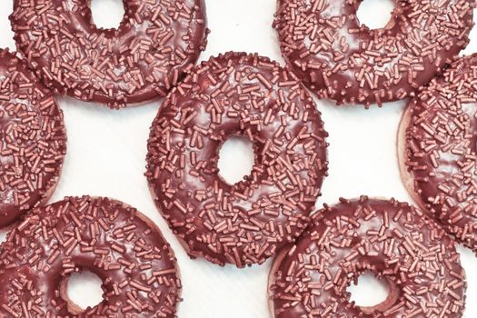 Chocolate ring donuts on a white cardboard surface