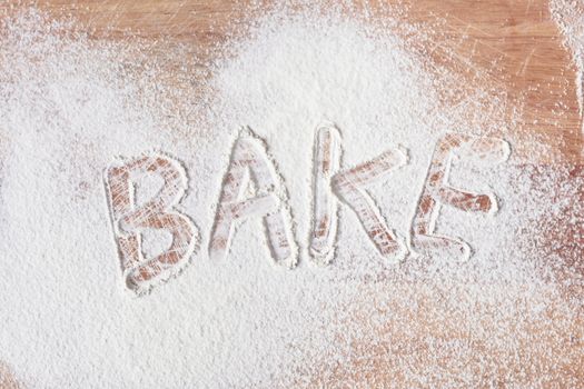 Bake written in flour on a wooden surface