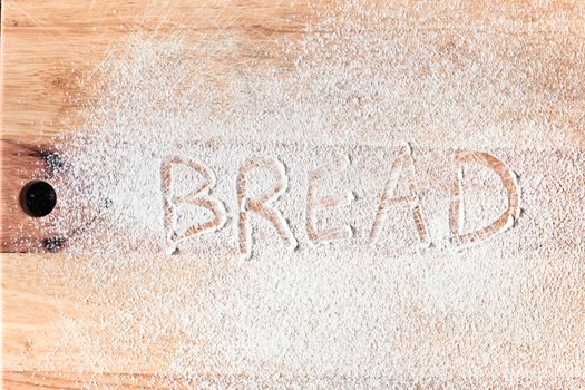 Bread written in flour on a wooden surface